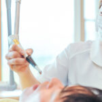 歯科ユニットで横になる患者と治療をしている歯科衛生士