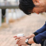 外のベンチに座ってつらそうにするサラリーマン