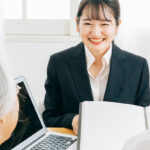 老夫婦にパソコンや書類を見せて説明するビジネスマン