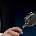 「調査」を象徴する虫眼鏡を持つ人