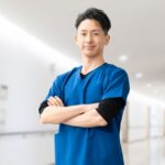 病院の廊下で腕組みをしてこちらを見つめる男性医師
