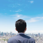 空を見つめるサラリーマンの後ろ姿