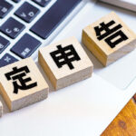 確定申告と書かれた木のブロックとパソコンと電卓