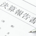 決算報告書の書類とその上に置かれたボールペン