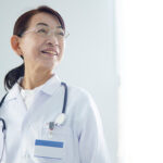 聴診器を肩にかけ白衣を着た老年女性医師