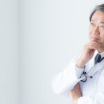 何か考え事をするような表情をした、白衣姿の男性医師